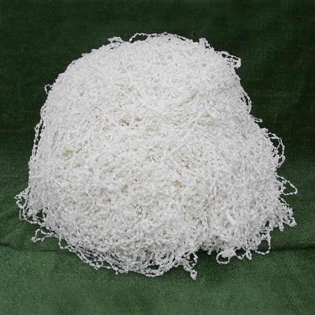 A white ball of shredded paper on top of green cloth.